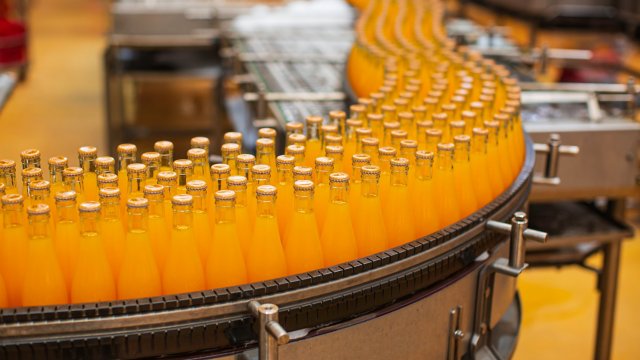 食品和飲料：果汁瓶沿傳送帶向下移動